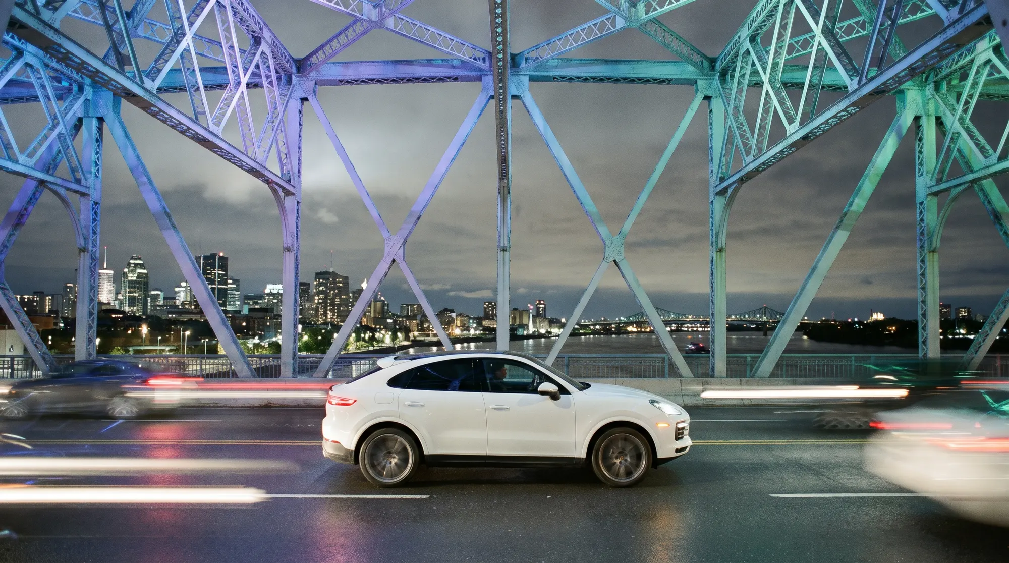 A white Porsche Cayenne Coupe crossing the Jacques Cartier Bridge at night