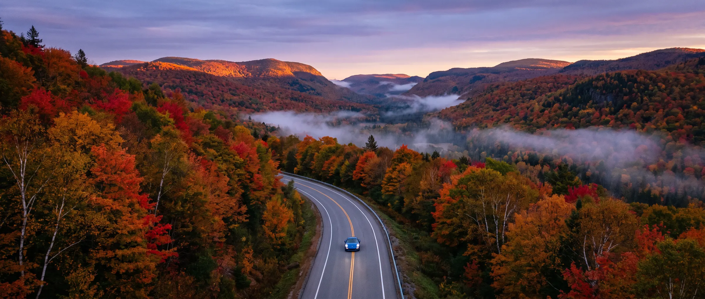 A blue Porsche 911 on a winding road through the Laurentides in October