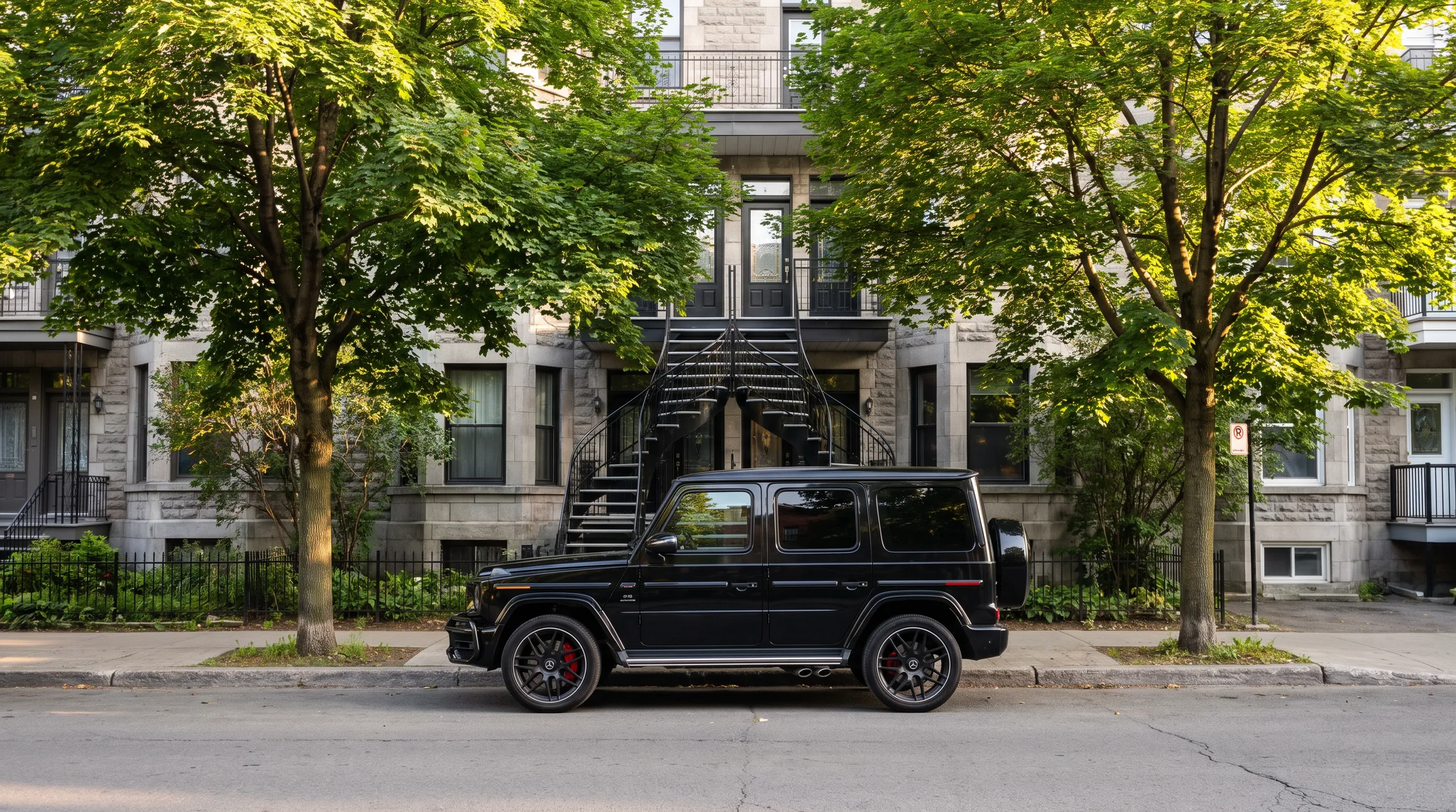 A black G 63 parked on an Outremont street in summer